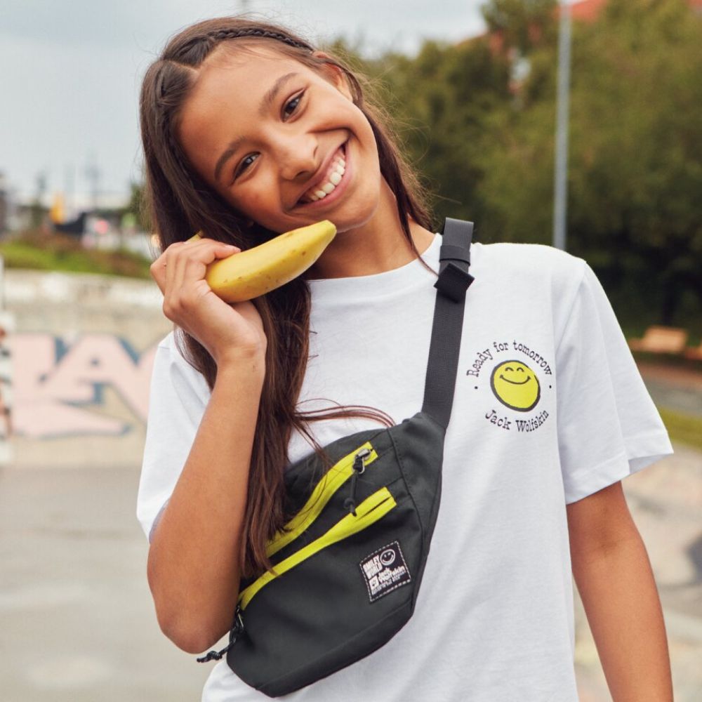 Girl holding a banana to her ear and smiling at the camera